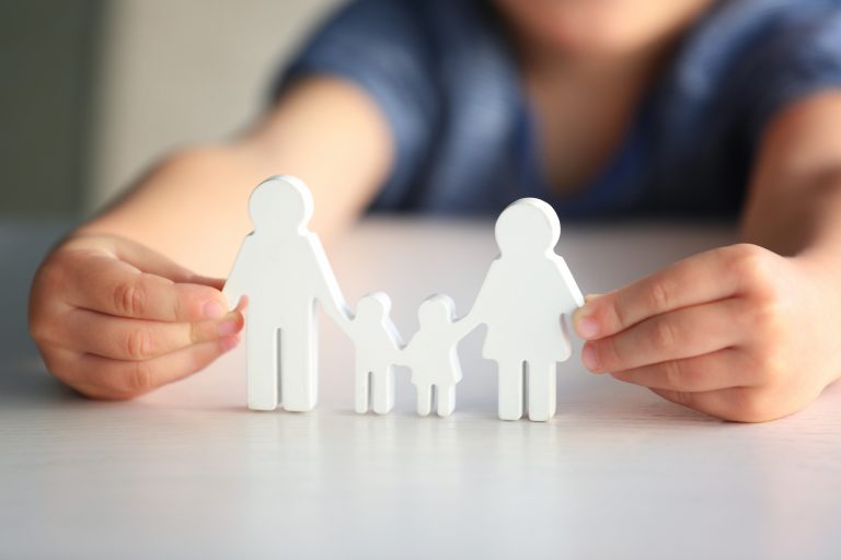 Child holding figure in shape of happy family, closeup. Adoption concept